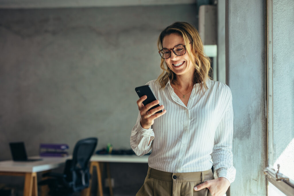 smiling businesswoman using phone in office