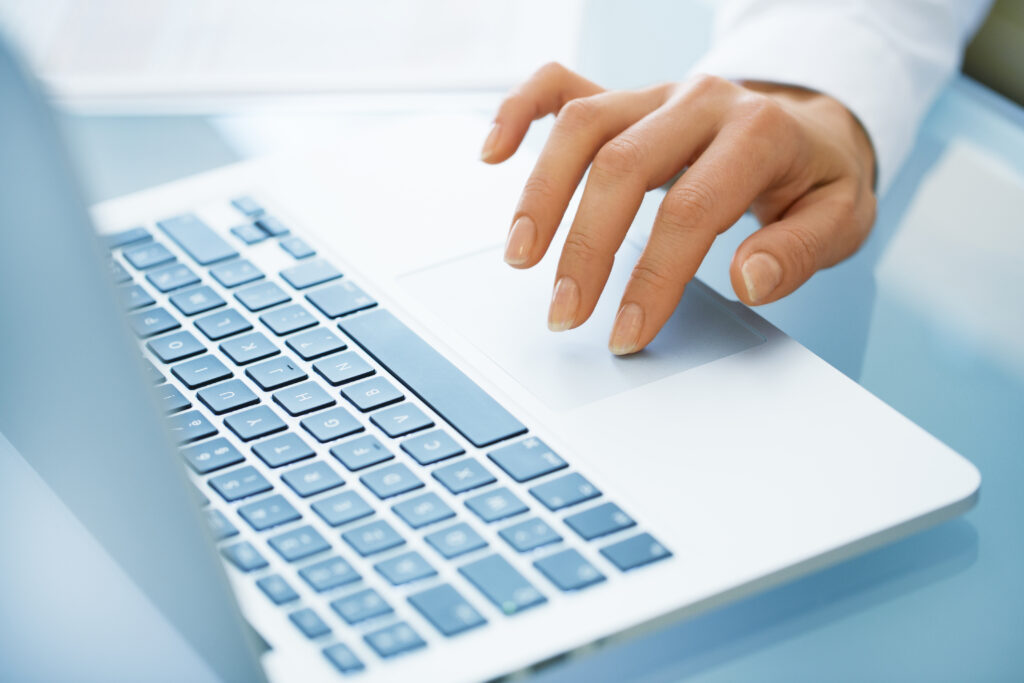 close up of woman hands using a laptop computer on desk