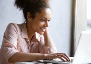 woman smiling while looking at laptop