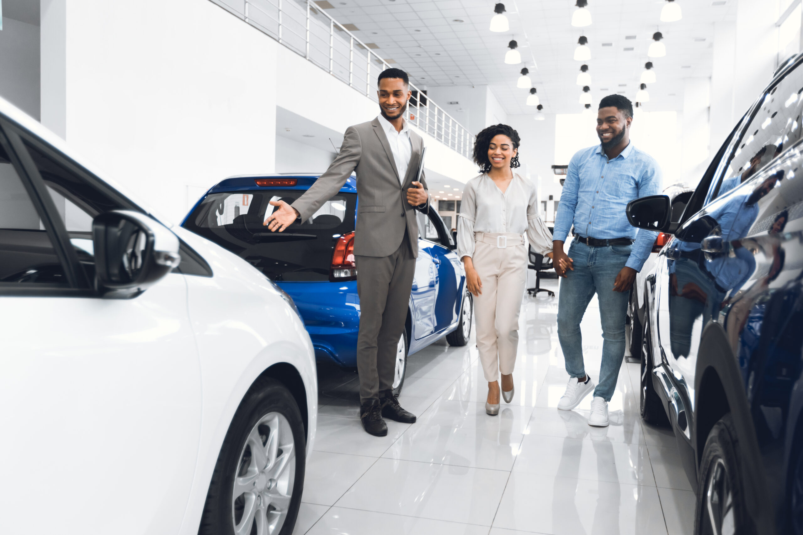 A car salesman showing a man and a woman a car