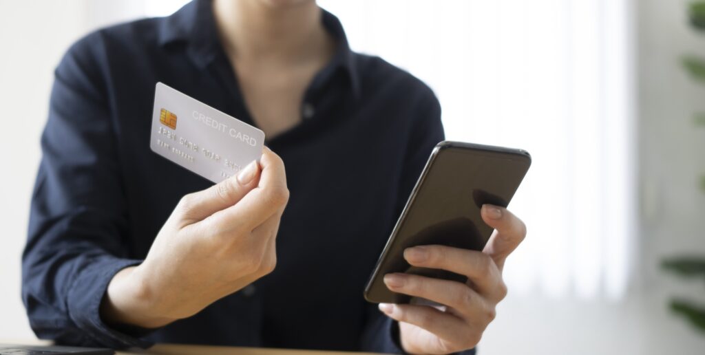An image of a person with a credit card and phone